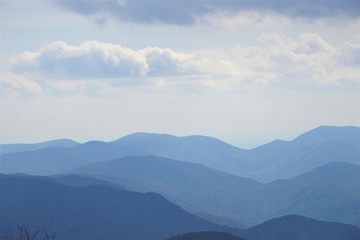 The fantastic view from Brasstown Bald mountain ( the highest mountain in Georgia) on a hazy day, mountains looks silhouette with white fluffy clouds and blue sky, North Georgia in USA.