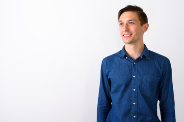 Studio shot of happy young handsome man smiling and thinking whi