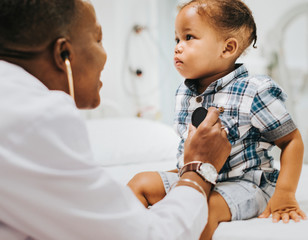 Wall Mural - Cheerful pediatrician doing a medical checkup of a young boy