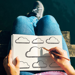 Wall Mural - Woman drawing empty clouds in a notebook