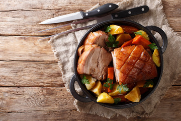 Wall Mural - Tasty crispy pork baked in beer with vegetables and gravy close-up in a frying pan. horizontal top view