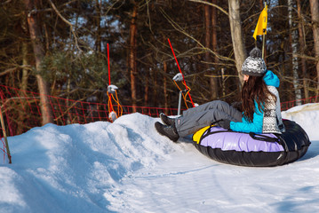 young smiling girl ride sleigh snow tubing hill winter activity