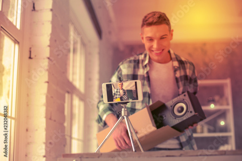 Fotografía Joyful young blogger showing item hes opening