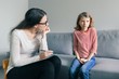Professional child psychologist talking with child girl in office