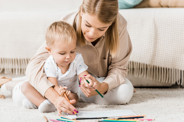 Wall Mural - mother and adorable toddler drawing together in nursery room