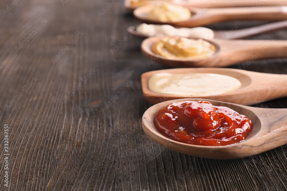 Spoons with tasty sauces on wooden table