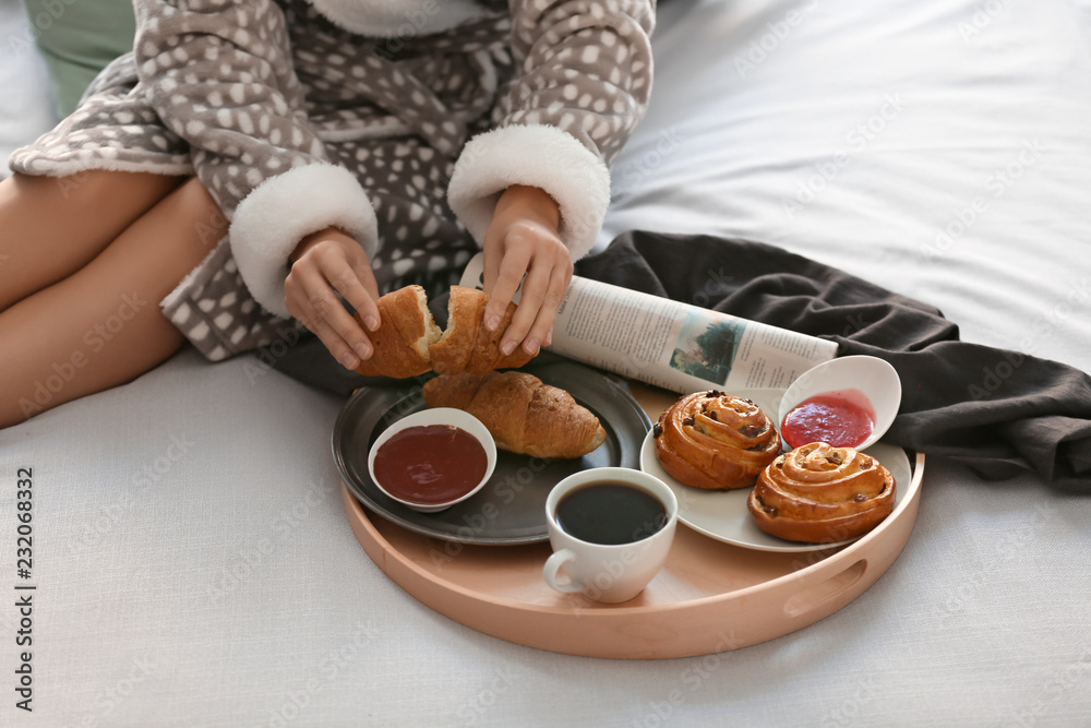 Young woman having delicious breakfast on bed