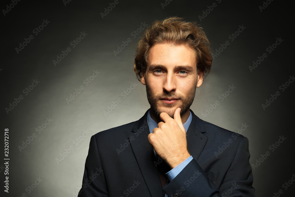 Portrait of young handsome businessman on black background