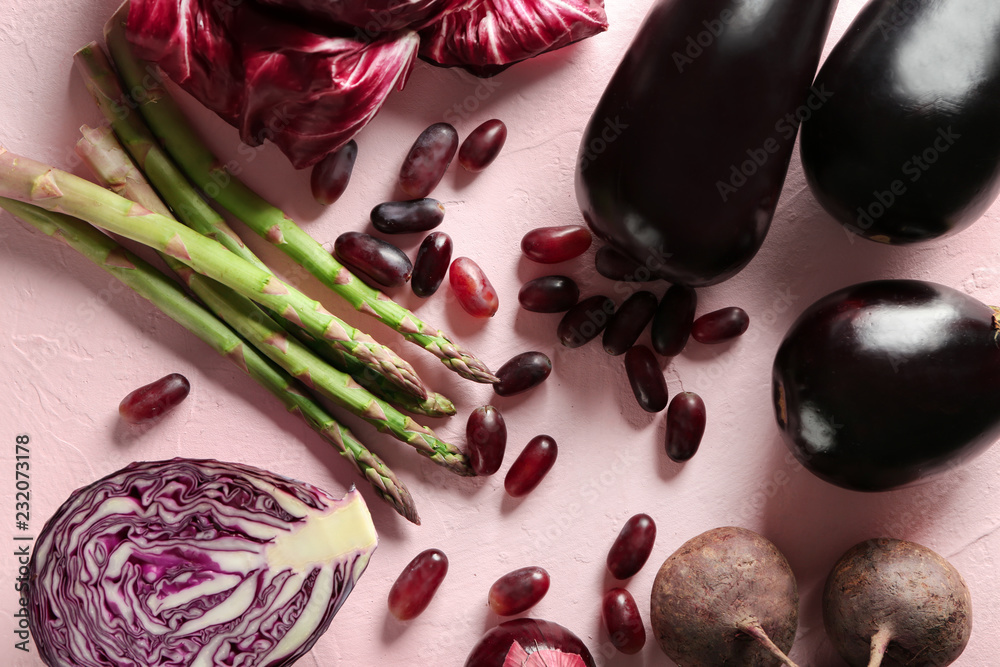 Various fresh vegetables with grapes on color background