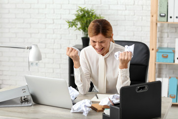 Wall Mural - Stressed woman crumpling paper at workplace