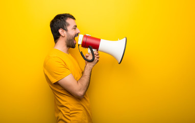 Wall Mural - Man on isolated vibrant yellow color shouting through a megaphone to announce something in lateral position