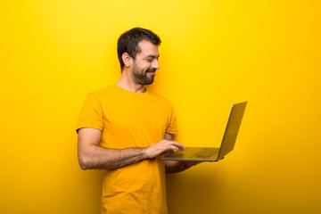 Wall Mural - Man on isolated vibrant yellow color with laptop