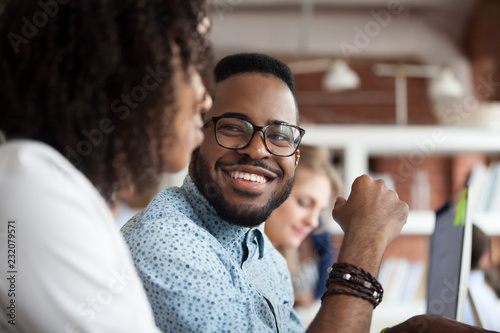 Fotomural Close up of smiling African American employee look at female colleague chatting