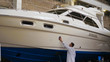 Young man (guy) specialist in white work coat polishes the yacht in the garage. Concept of: Yacht preparation, Cleaning, Polishing, Master, Professional, After painting, Using chemistry.