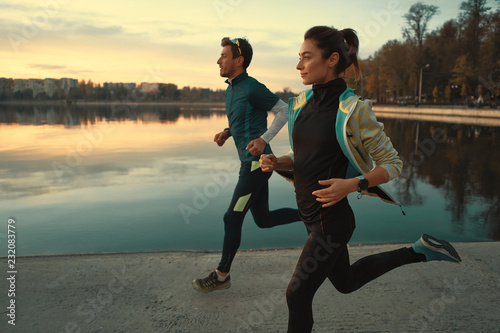 Fényképezés  Young man and woman out for a run on the lake at the sunrise
