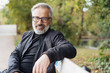 © contrastwerkstatt - Happy middle-aged man relaxing on a park bench