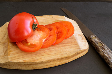 tomato sliced on a wooden Board. black background