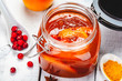 Persimmon jam in glass jar on wooden  background. Close up