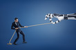 © gearstd - A small businessman tugs a long rope competing with a giant robotic hand.