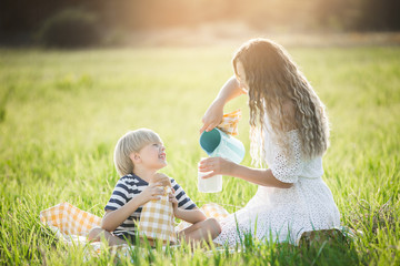 Happy family having picnic. Adorable children with their mother drinking fresh milk