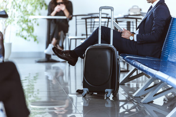 businessman with digital tablet sitting at departure lounge in airport