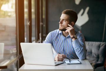 Wall Mural - Young man drawing template for the web site associated with digital marketing, current trends and tendencies of UX / UI design. Businessman who rules his company remotely, like a freelancer