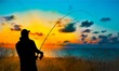 Silhouette of fishing man on coast of sunset sea