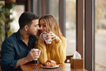 Wall Mural - Young couple in love sitting in a cafe, drinking coffee