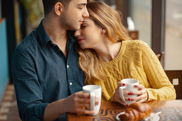 Wall Mural - Young couple in love sitting in a cafe, drinking coffee