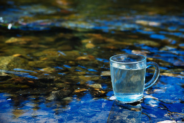 Glass Cup on the background of a pure mountain spring. The concept of clean water