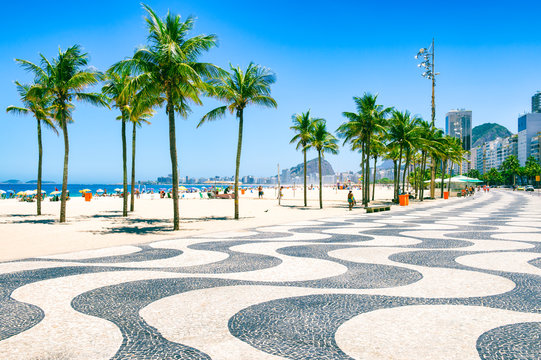 bright morning view of the curving boardwalk tile pattern with palm trees at copacabana beach with t