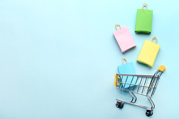 small paper shopping bags with shopping cart on blue background