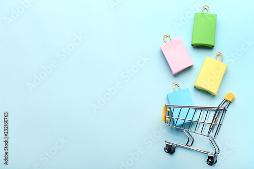 Cuadros en Lienzo Small paper shopping bags with shopping cart on blue background