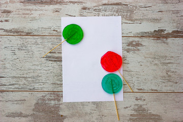 Flat lay with white sheet and blue red and green lollypops