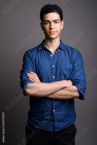 Fotografía Portrait of young handsome businessman against gray background