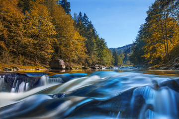 long waterfall and river with rocks high in the mountains. autumn mountains landscape. idea for outd