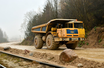 Heavy large quarry dump truck. The work of construction equipment in the mining industry. Production useful minerals. Sand transportation.