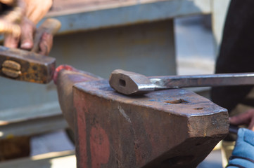 blacksmith performs the forging of hot glowing metal on the anvil