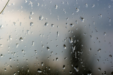 raindrops on window glass on background of cloudy sky