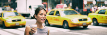 New York City Commute - Asian Business Woman Walking To Work In The Morning Commuting Drinking Coffee Cup On NYC Street With Yellow Cabs In The Background Banner. People Commuters Lifestyle.