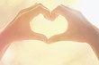 © photolink - Female hands heart shape on nature sun light flare and blur leaf abstract background.