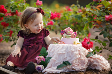 Little girl and decorated party with a cake in the flowers garden