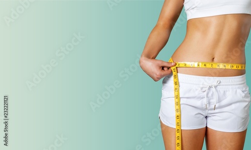 Fotomural Slim young woman measuring her thin waist