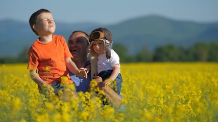 Wall Mural - Father with two sons appearing from blossom rape field, have fun in nature