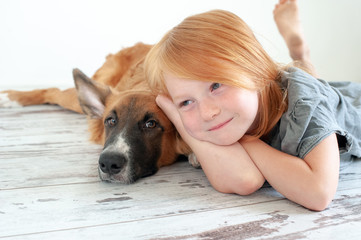 Wall Mural - Red-haired puppy and red-haired girl lie on the floor