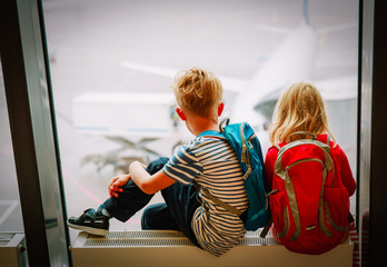 little boy and girl waiting for plane in airport