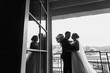 © sonyachny - Gorgeous bride and stylish groom silhouettes at window light. Sensual wedding couple embracing. Romantic moments of newlyweds. Creative wedding photo. Copy space