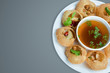 Delicious favorite north and south indian street food pani puri gol gappa with tamarind water served in white plate with mashed potato and chickpeas