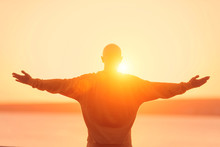 Young Athletic Man Rising Hands On Sunset Sky. Meditation, Yoga, Freedom And Healthy Lifestyle Concept