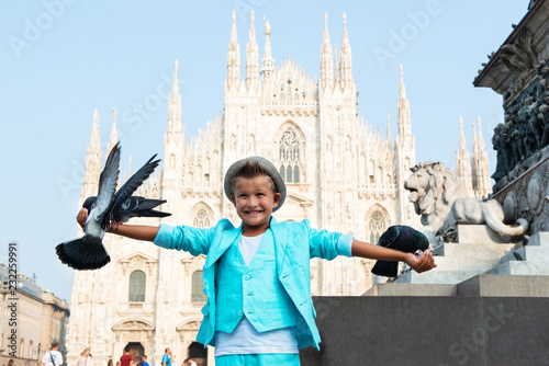 Fotomural Young boy posing with pigeons in the milanese street with ancient church Duomo di Milano on background
